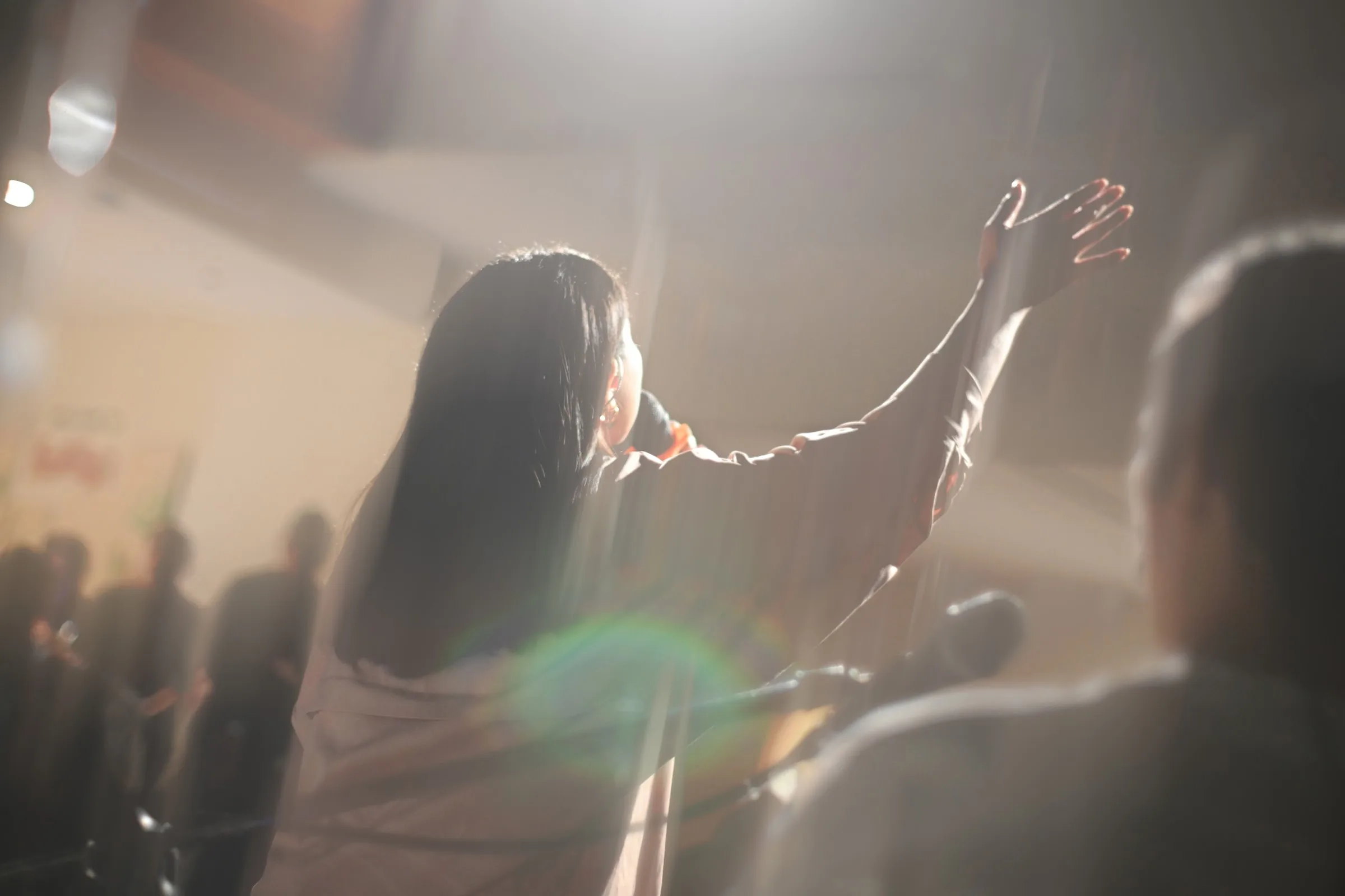 People worship together with raised hands in a gathered community