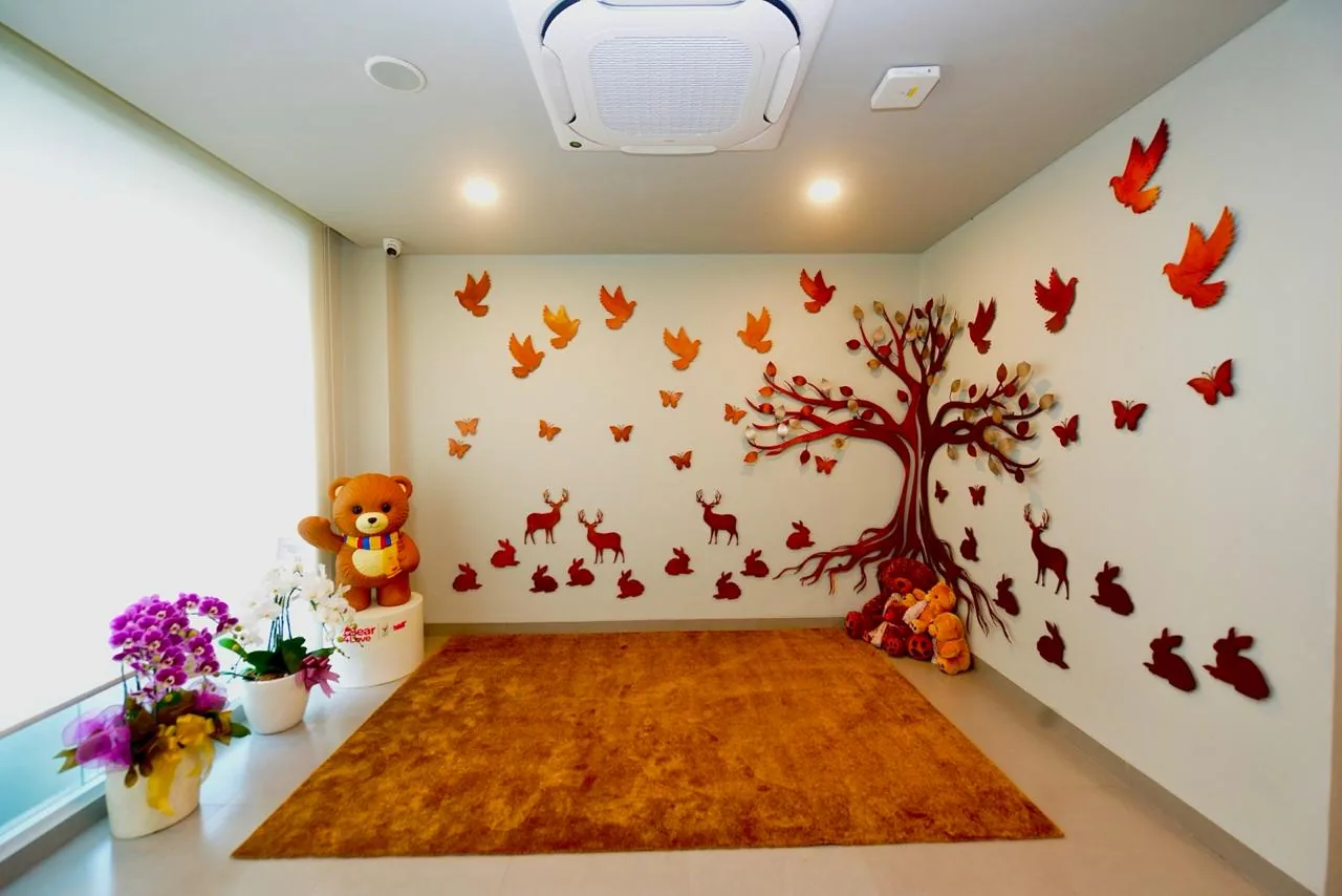 A bright children's room decorated with a tree, birds, and toys