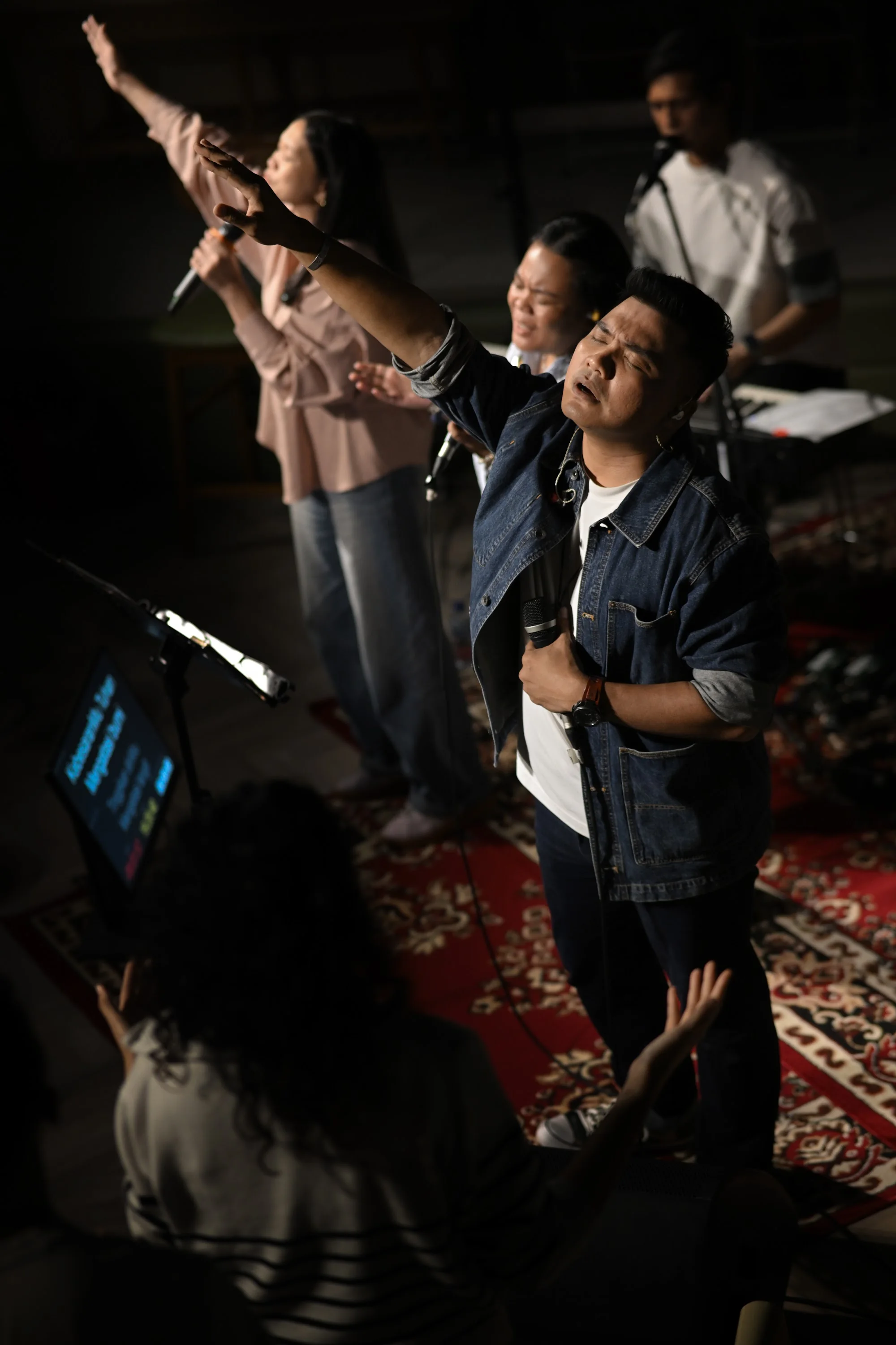 A worship leader holds a microphone with one hand lifted during City Soul Vol. 3